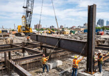 A construction site showcasing the installation of custom fabricated steel beams for a new building foundation.